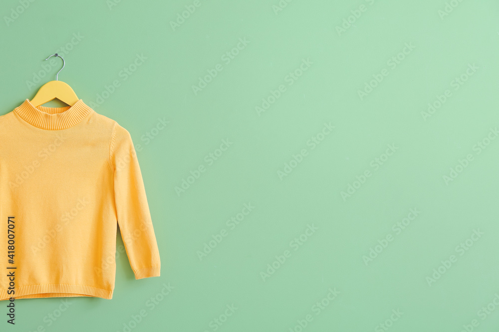 Hanger with sweater on color background