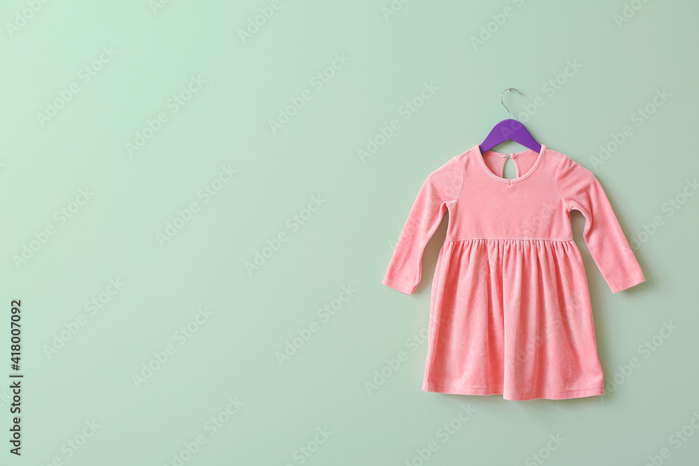 Hanger with dress on color background