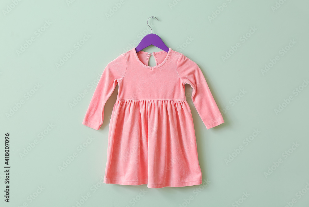 Hanger with dress on color background