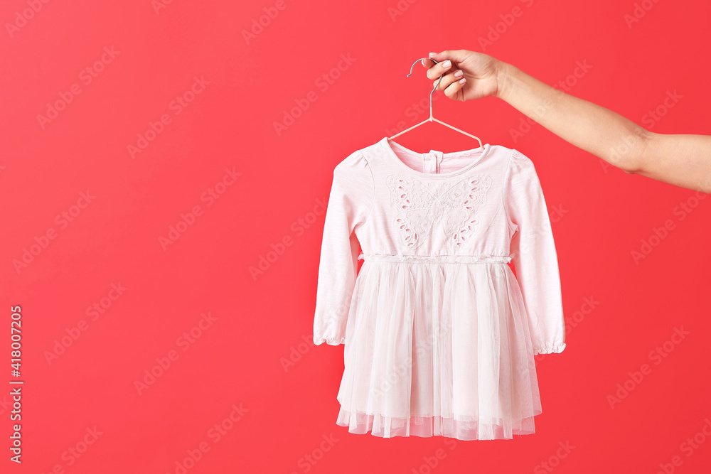 Woman holding hanger with dress on color background