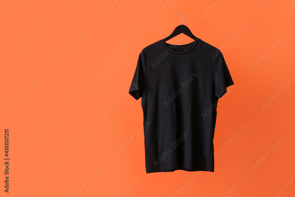 Hanger with t-shirt on color background