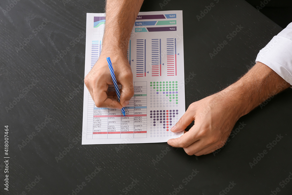 Young businessman working on dark table in office