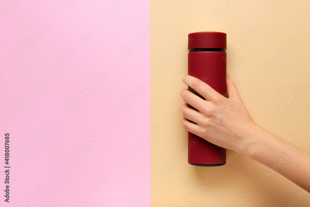 Female hand with modern thermos on color background