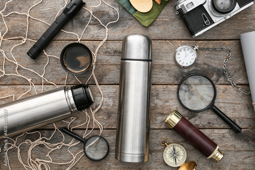 Modern thermos and items for travel on wooden background