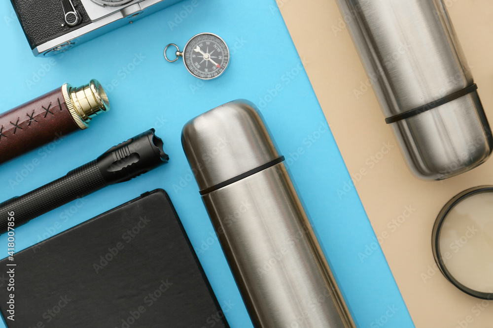 Modern thermos and items for travel on color background