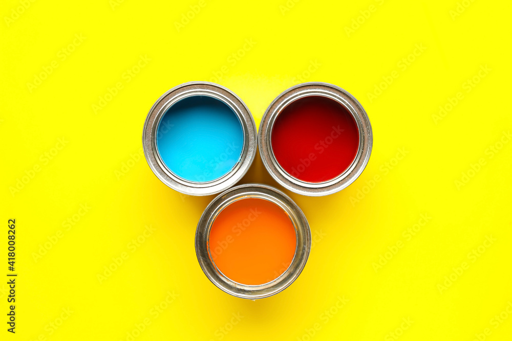 Cans of paints on color background