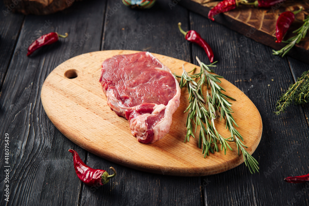 Side view on raw piece of meat with rosemary on the wooden board