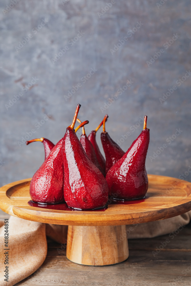 Dessert stand with sweet poached pears in red wine on dark background