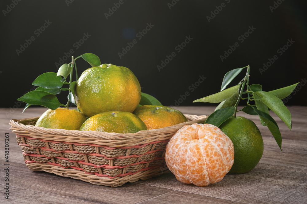 Fresh green tangerine mandarin orange on dark wooden table background.