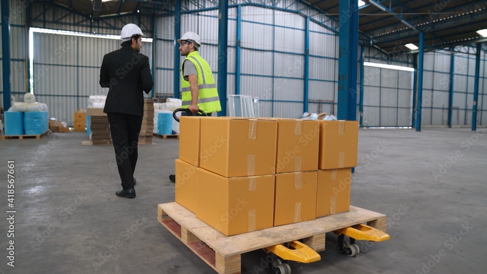 Factory workers deliver boxes package on a pushing trolley in the warehouse . Industry supply chain 