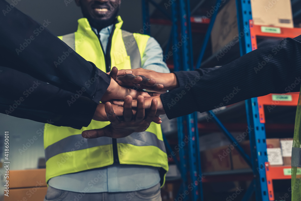 Factory workers stacking hands together in warehouse or storehouse . Logistics , supply chain and wa