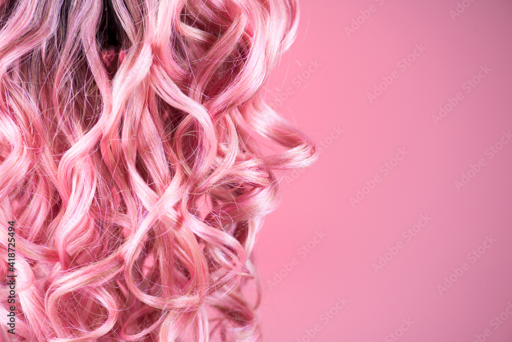 Hair. Beautiful healthy long curly dyed pink color hair close-up texture. Fashion trendy Dyed wavy h