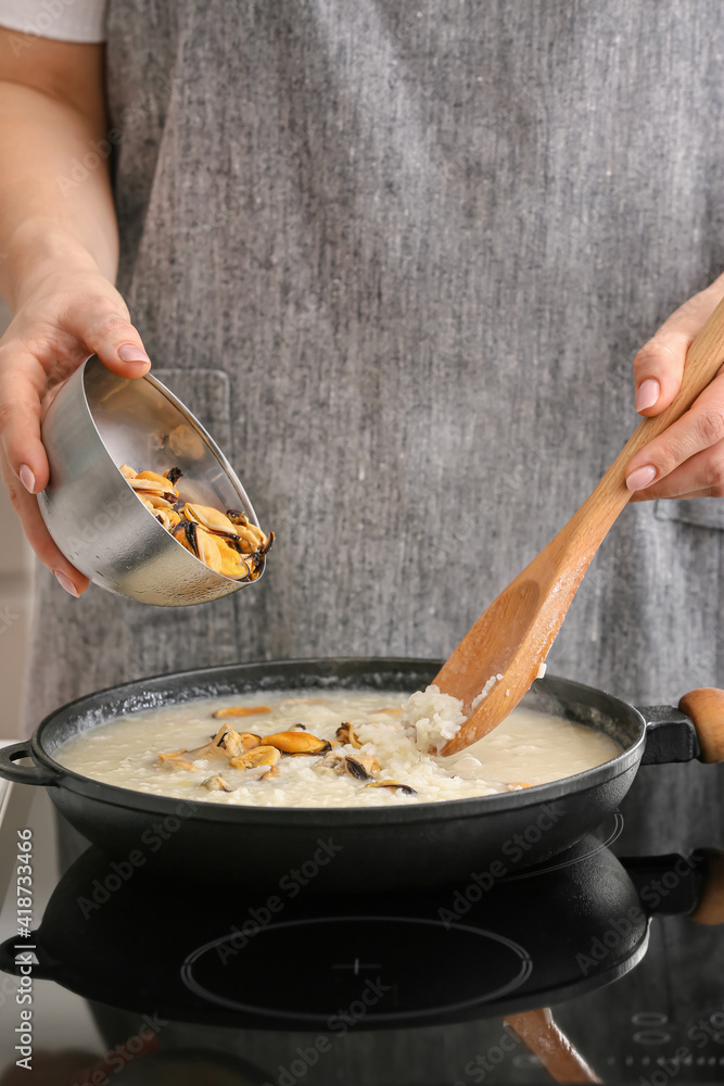 Woman cooking risotto in kitchen