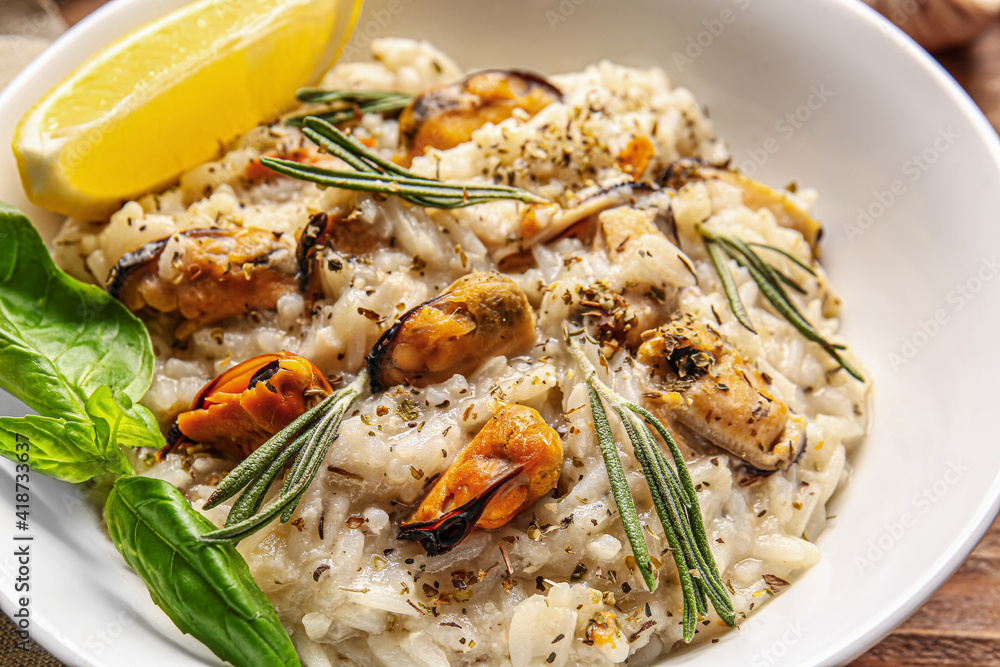 Plate with tasty risotto on wooden background, closeup