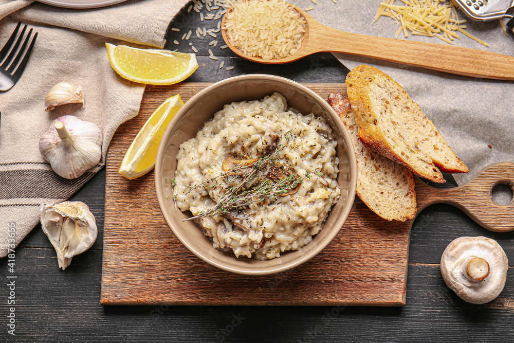 Bowl with tasty risotto on dark wooden background