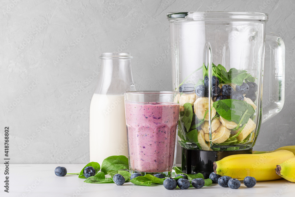 Glass of healthy smoothie or milkshake made of blueberry, banana, almond milk and spinach with blend