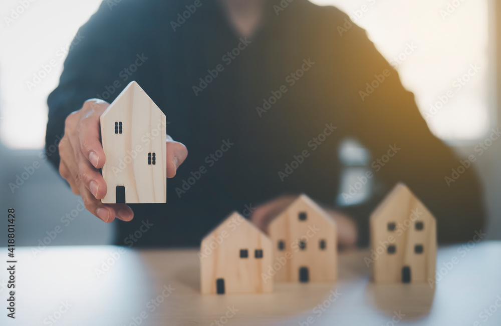 Man hand choosing mini wood house model from model on wood table, Planning buy Real Estate, Planning