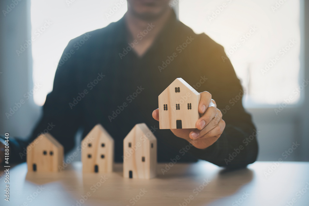 Man hand choosing mini wood house model from model on wood table, Planning buy Real Estate, Planning