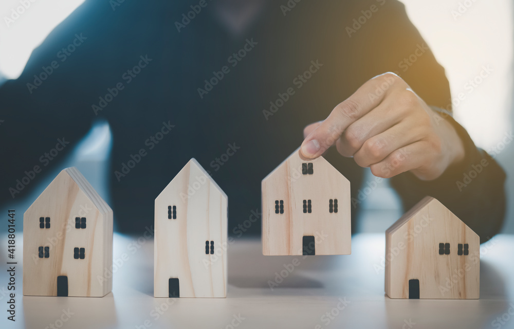 Man hand choosing mini wood house model from model on wood table, Planning buy Real Estate, Planning