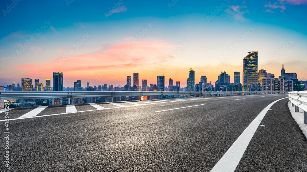 Empty asphalt road and city skyline with buildings at sunset in Shanghai.