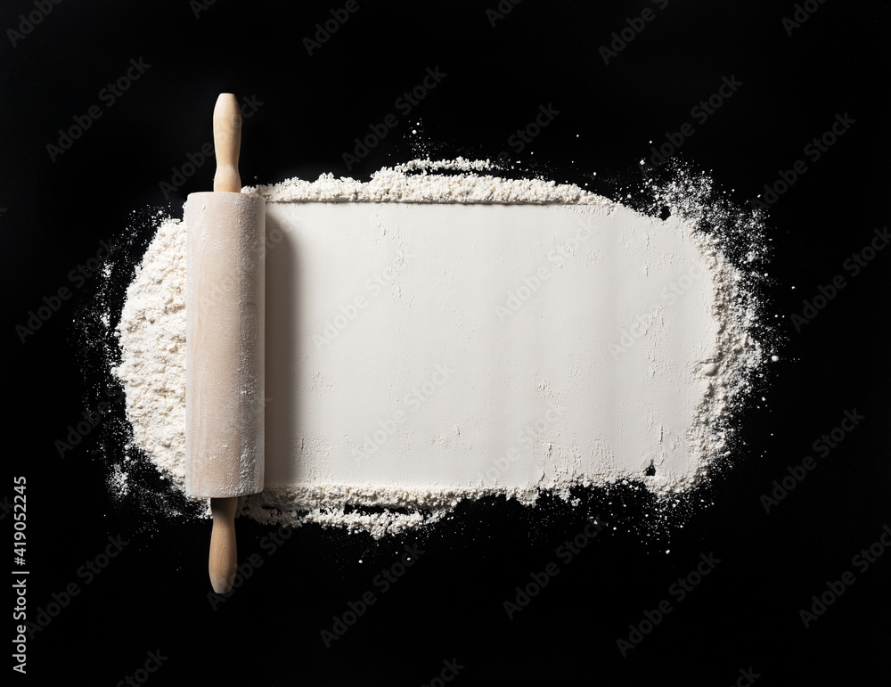 Bake background with free space for text. Rolling pins and flour on a black table.