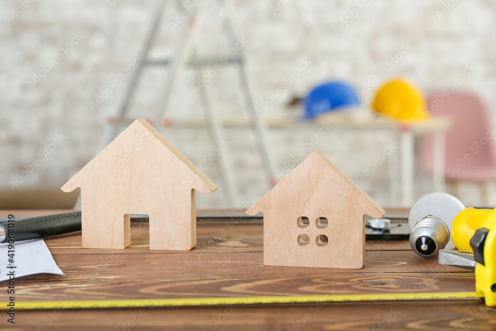 Figures of house with builders supplies on wooden table