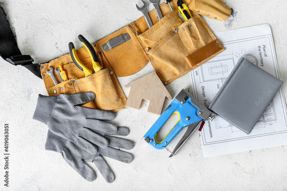 Figure of house and construction tools on light background