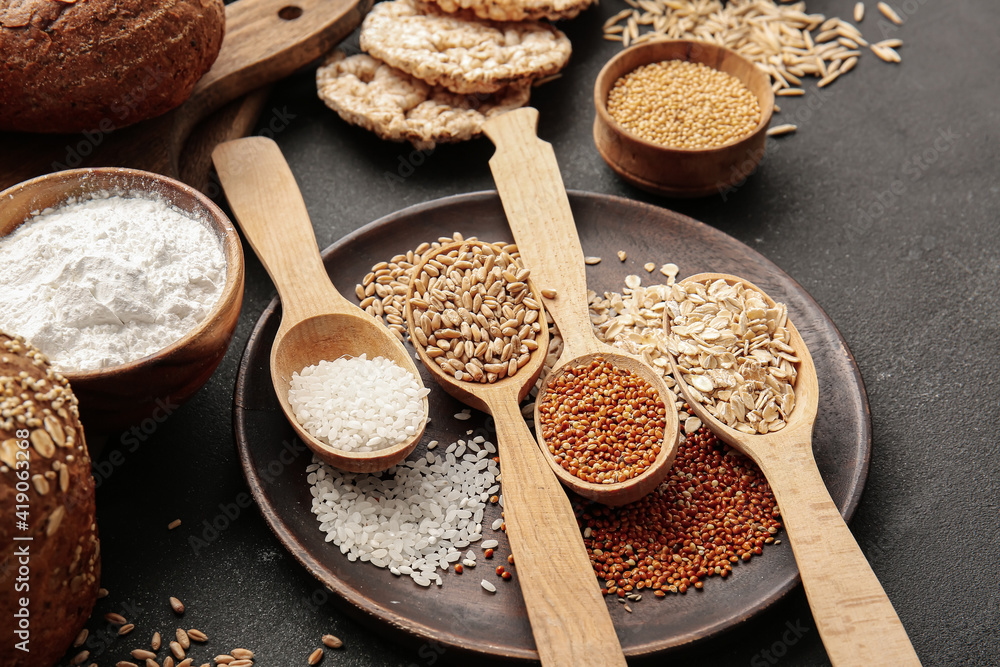 Spoons with different cereals on dark background, closeup