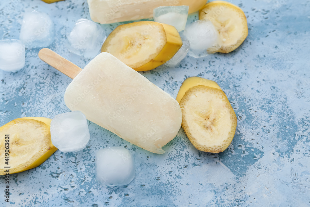 Tasty banana ice-cream and ice cubes on color background, closeup