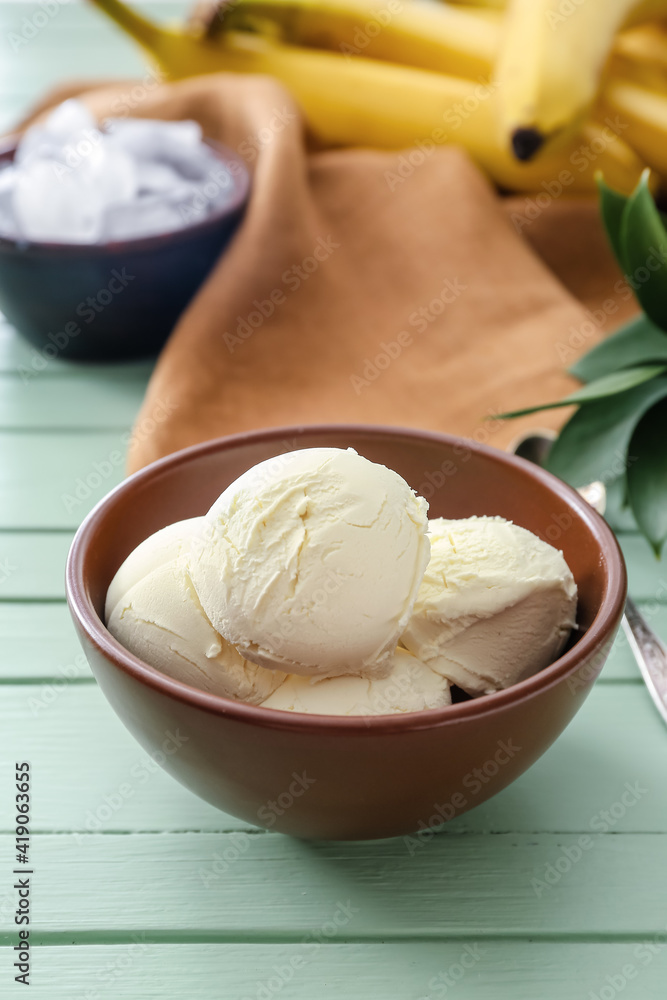 Bowl with tasty banana ice-cream on color wooden background