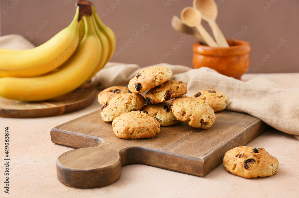 Board with tasty banana cookies on color background