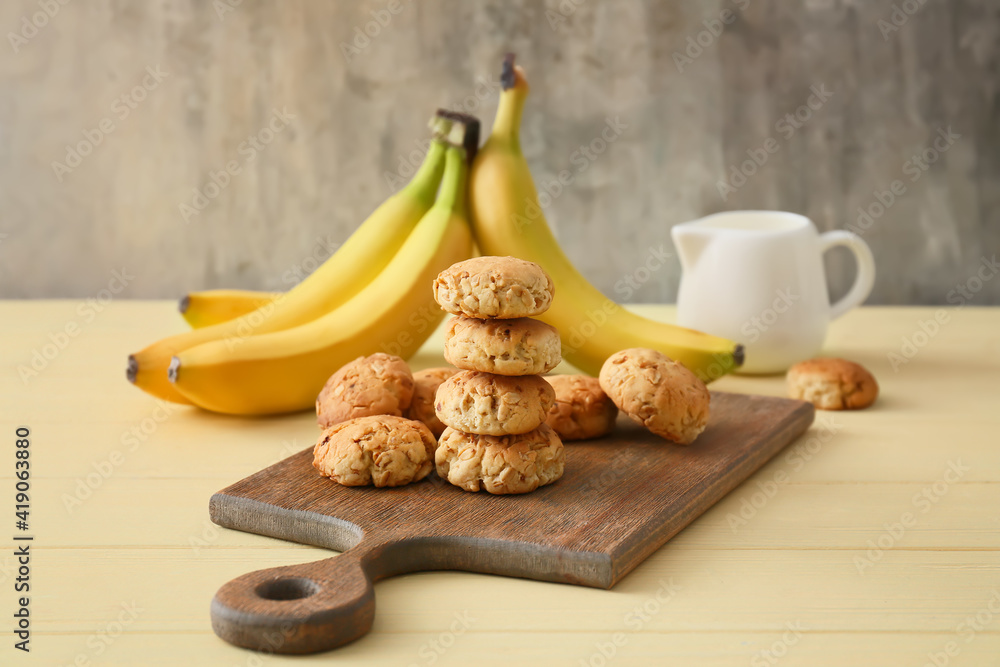 Board with tasty banana cookies on color background