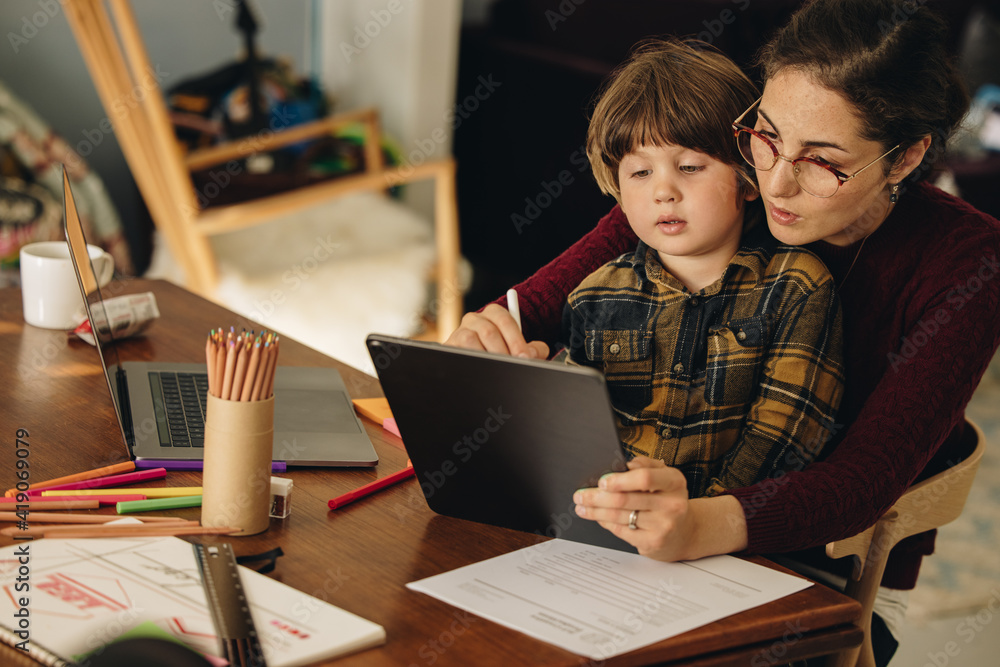 Mother teaching son drawing on digital tablet