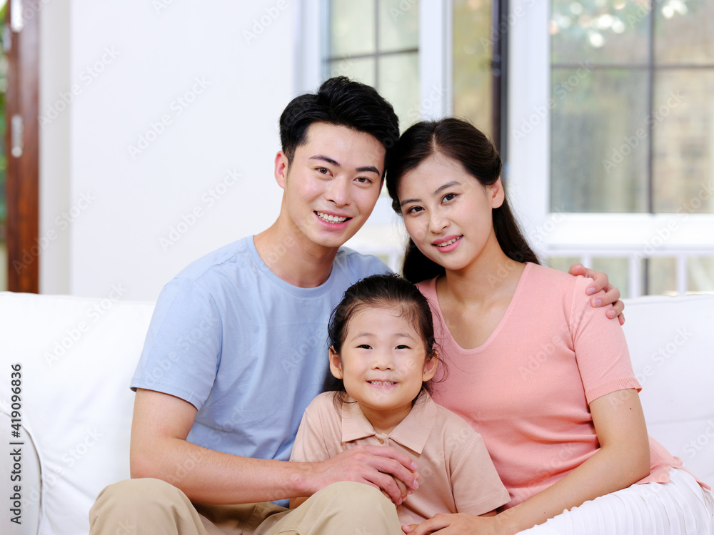 A happy family of three is sitting on the sofa in the living room