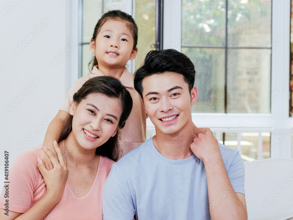 A happy family of three is sitting on the sofa in the living room