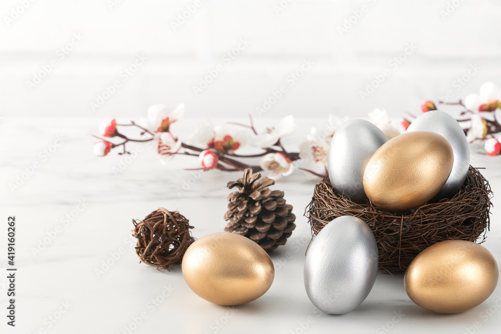 Close up of golden and silver Easter eggs in the nest with white plum flower.