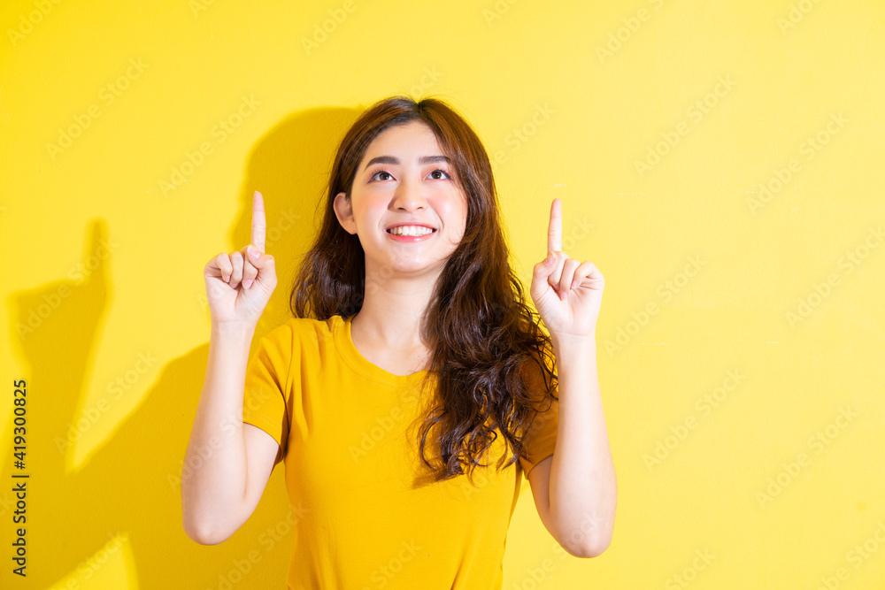 Young Asian girl posing on yellow background