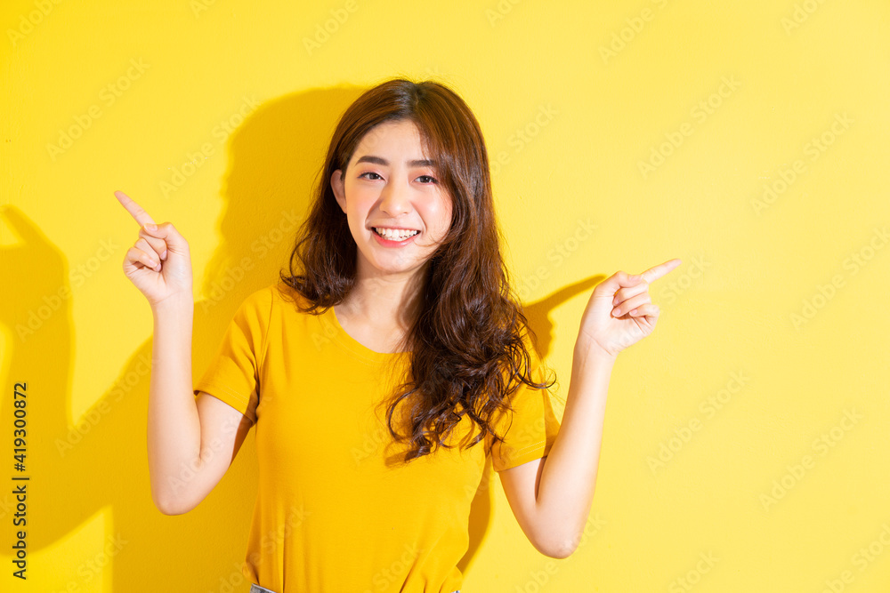 Young Asian girl posing on yellow background