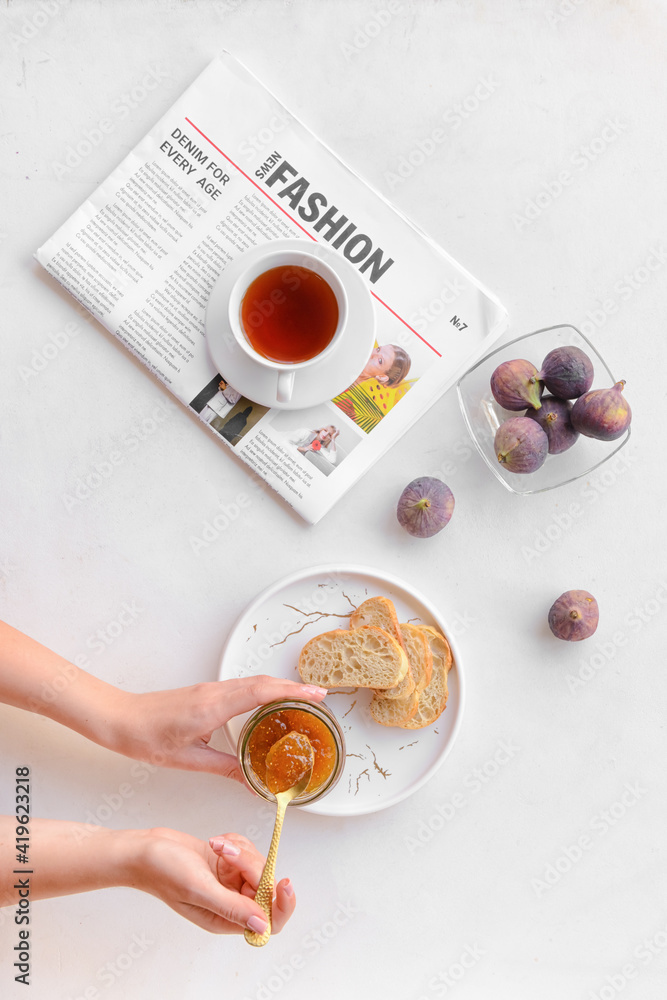 Woman with jar of sweet fig jam on table