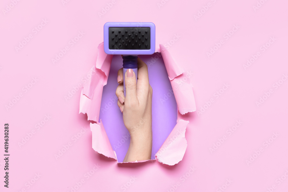 Female hand with brush for pet grooming on color background