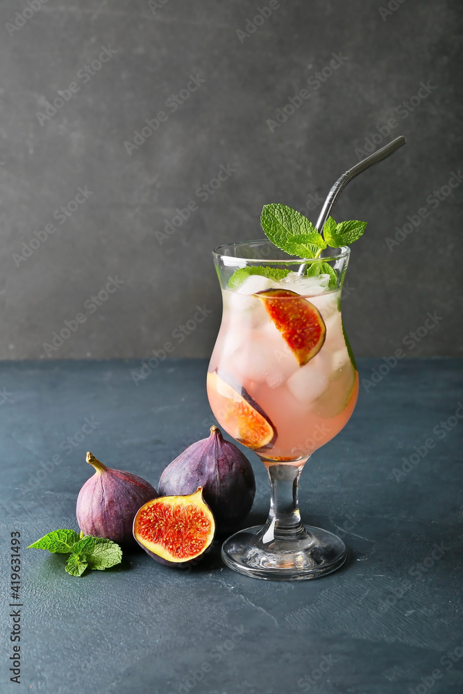 Glass of tasty fig lemonade on dark background