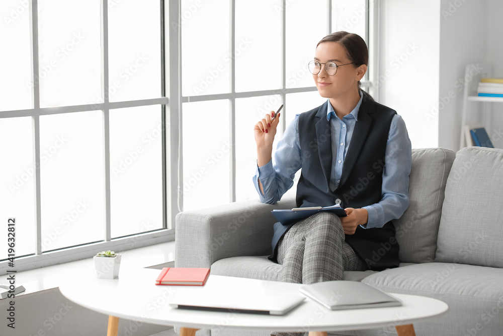 Portrait of female psychologist sitting on sofa in office