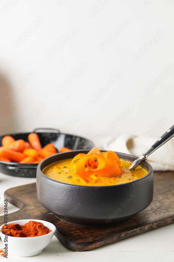 Cooking pot with tasty carrot cream soup on light background