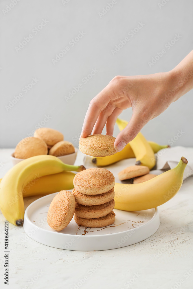 浅色背景下的美味香蕉饼干女性手