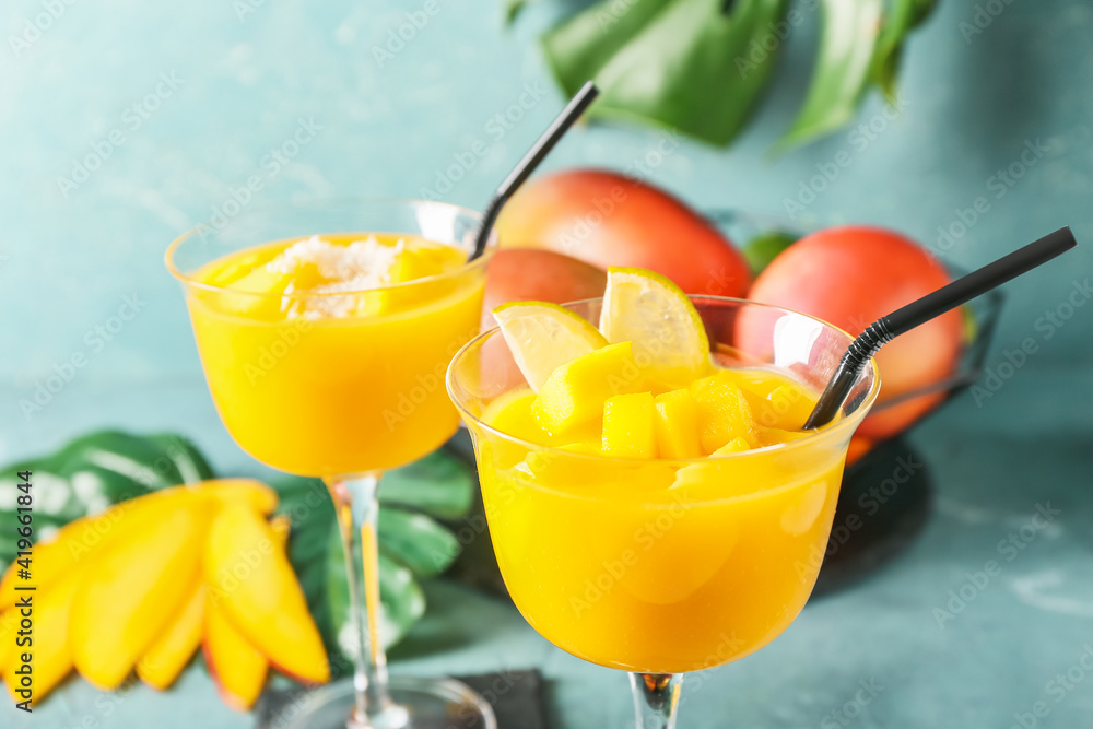 Glasses of mango margarita on color background