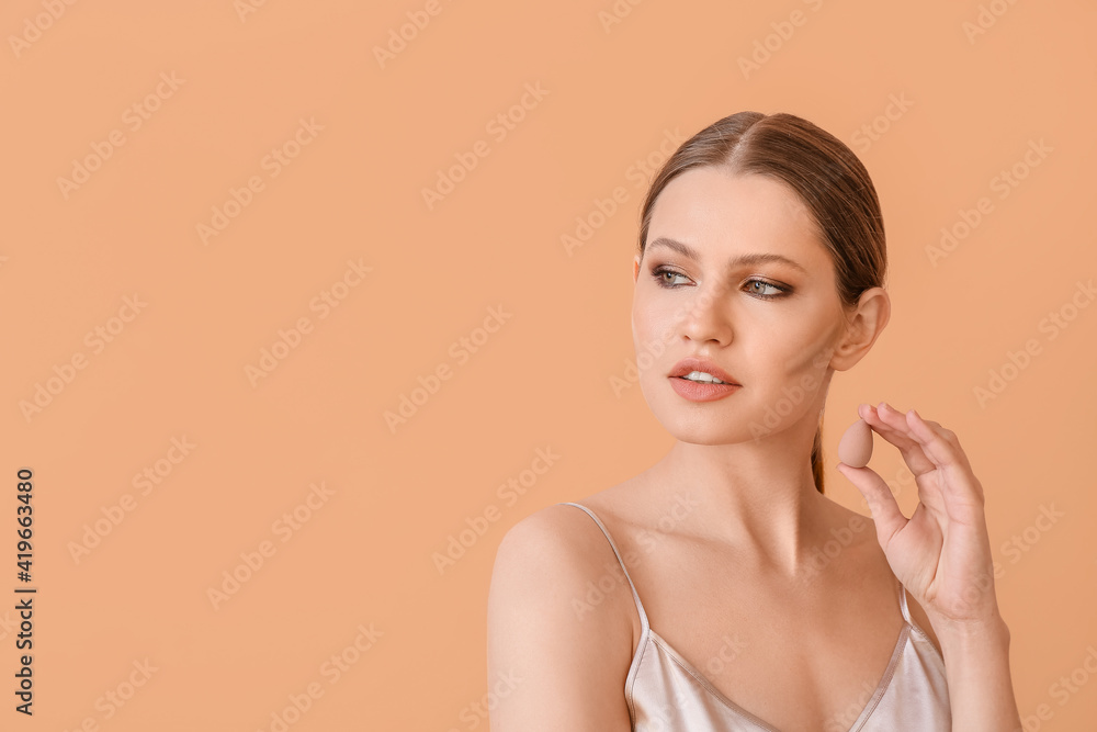 Beautiful young woman applying contouring makeup against color background