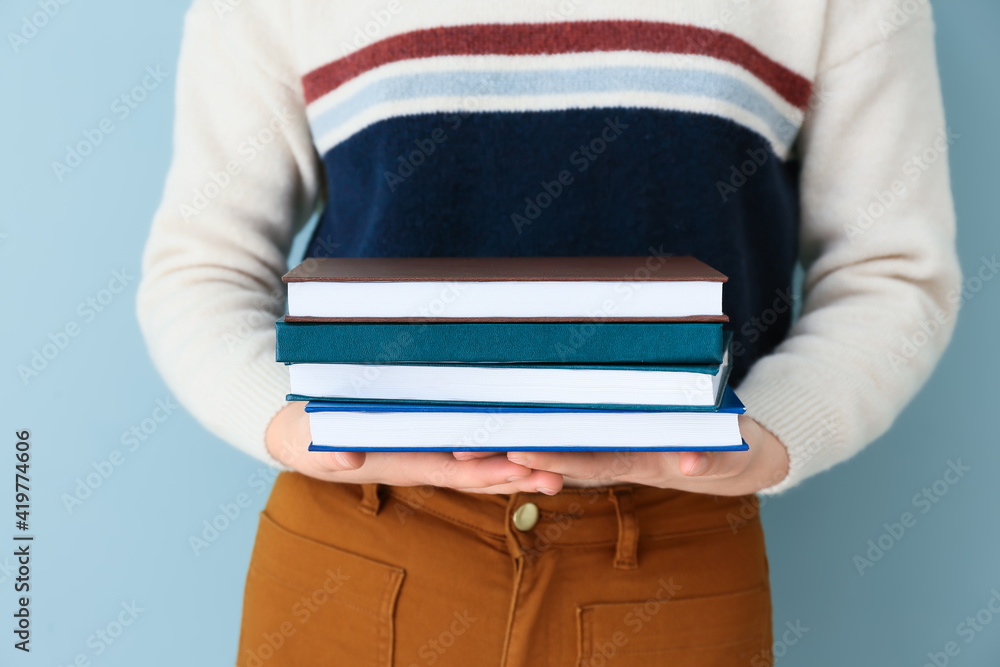 Woman with stack of books against color background