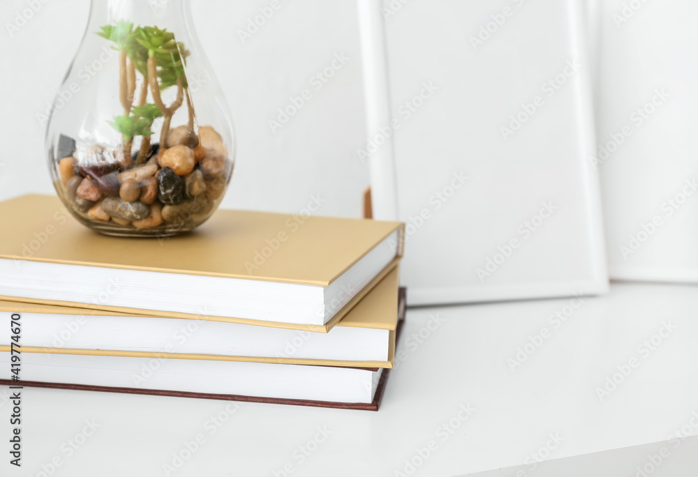 Stack of books on table against light wall