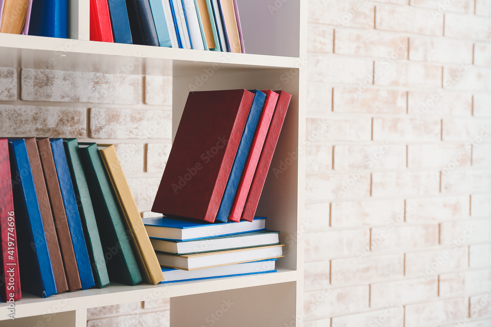 Many books on shelf against brick wall