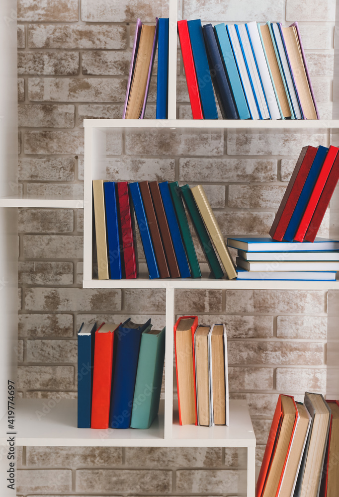 Many books on shelf against brick wall